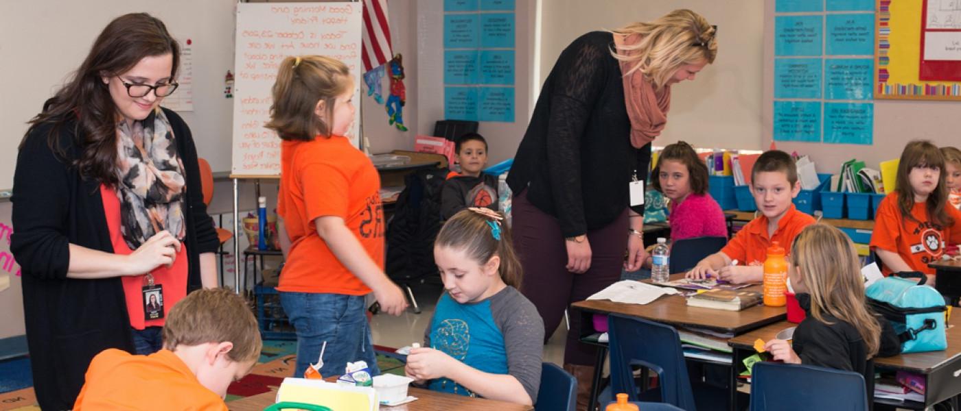 Two U N E liberal arts students work in a classroom with elementary school students